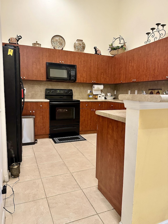 kitchen with light tile patterned flooring, a high ceiling, decorative backsplash, and black appliances