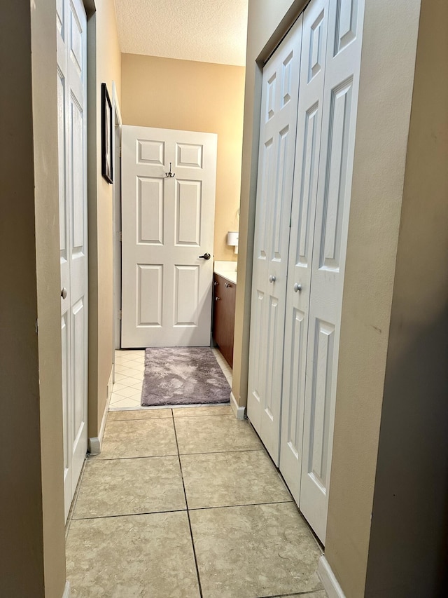 corridor featuring light tile patterned floors and a textured ceiling