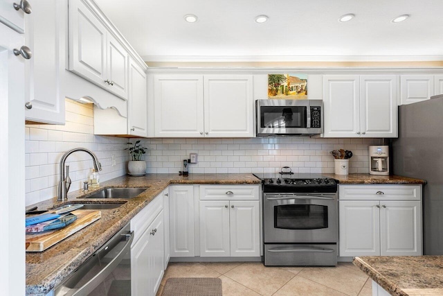 kitchen with sink, stainless steel appliances, dark stone counters, decorative backsplash, and white cabinets