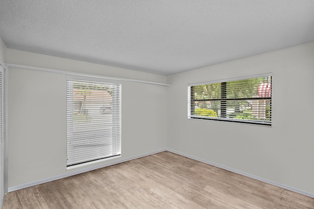 unfurnished room featuring a textured ceiling and light hardwood / wood-style floors