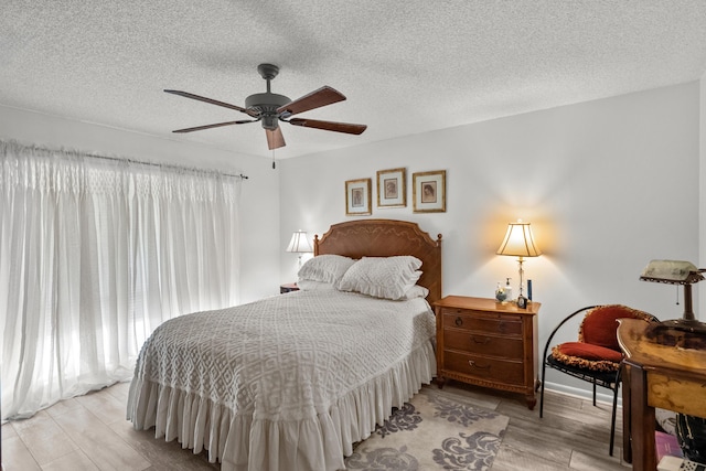 bedroom featuring ceiling fan, light hardwood / wood-style flooring, and a textured ceiling