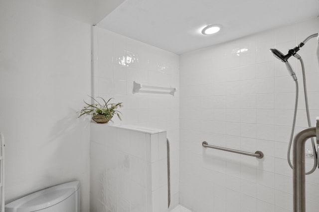 bathroom featuring toilet and a tile shower