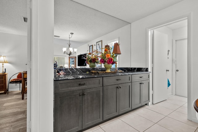 kitchen featuring gray cabinets, dark stone countertops, pendant lighting, and a textured ceiling