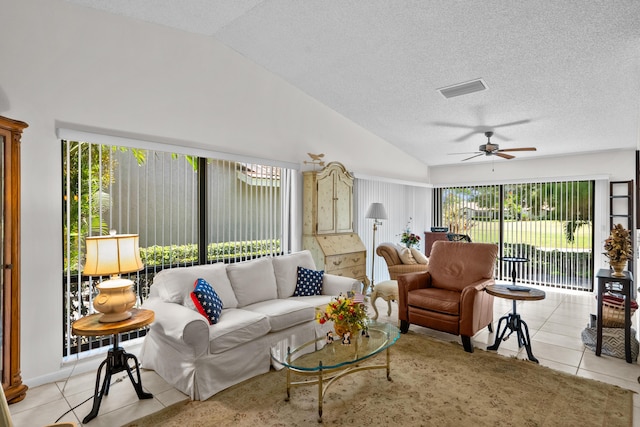 living room featuring ceiling fan, lofted ceiling, light tile patterned floors, and a textured ceiling