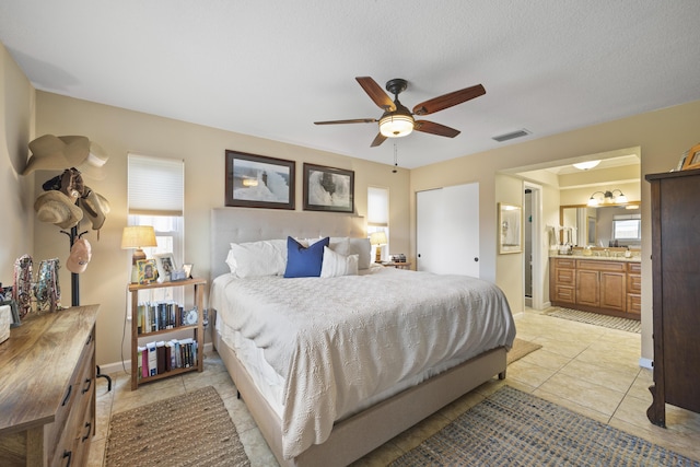 bedroom with light tile patterned flooring, ensuite bathroom, a textured ceiling, and ceiling fan