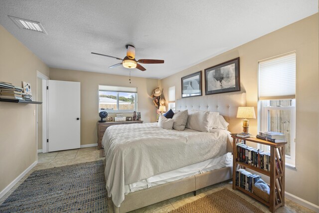 tiled bedroom featuring ceiling fan and a textured ceiling