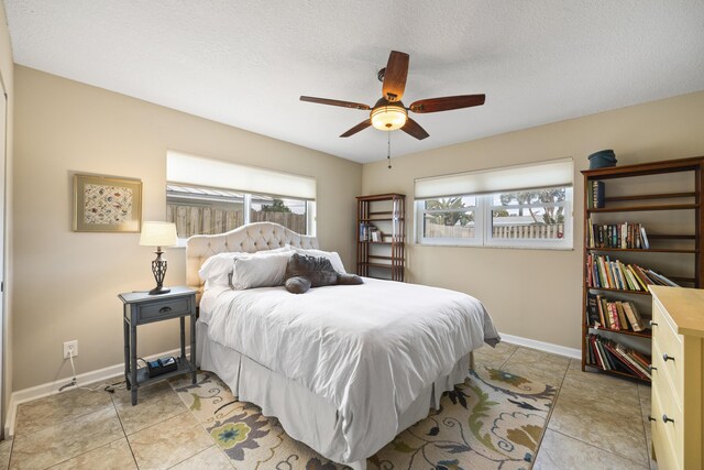 tiled bedroom with ceiling fan and a textured ceiling