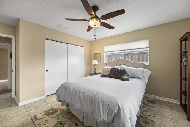 bedroom with light tile patterned flooring, a textured ceiling, ceiling fan, and a closet