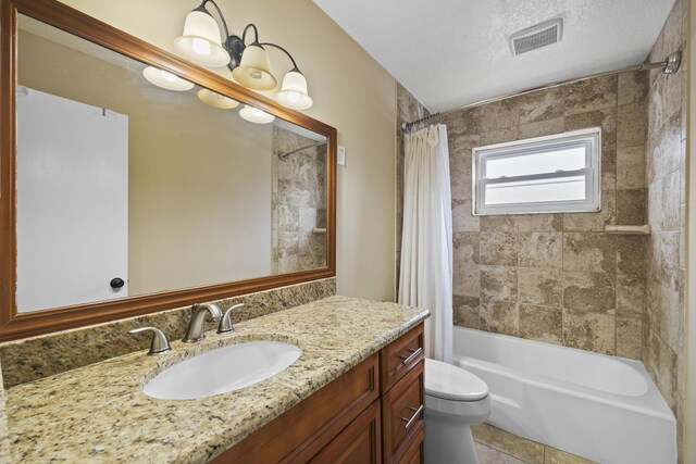 full bathroom with shower / tub combo with curtain, tile patterned flooring, vanity, toilet, and a textured ceiling