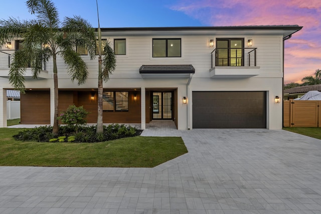 view of front of property with a lawn, a garage, and a balcony