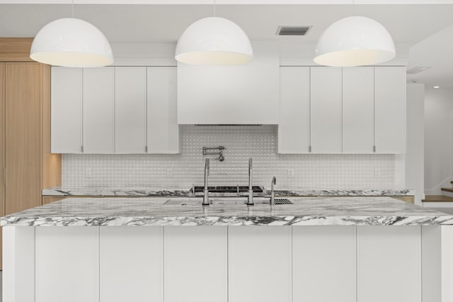 kitchen with tasteful backsplash, light stone counters, and white cabinets