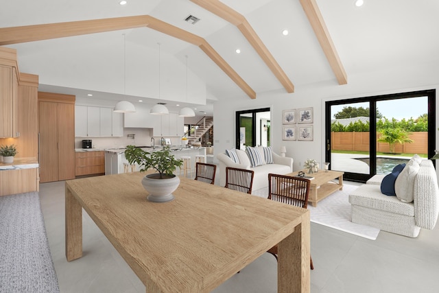 dining space featuring beam ceiling, sink, and high vaulted ceiling