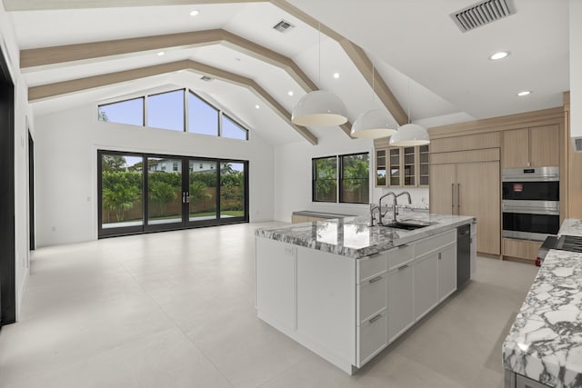 kitchen with white cabinetry, light stone countertops, sink, a large island with sink, and decorative light fixtures