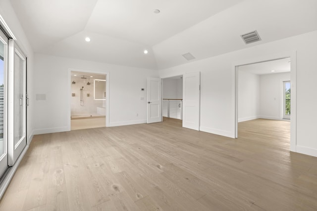 unfurnished bedroom with light wood-type flooring, connected bathroom, and vaulted ceiling