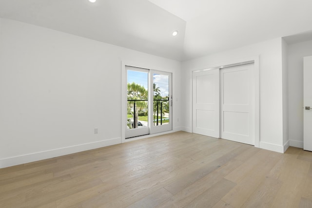 unfurnished bedroom with access to exterior, lofted ceiling, light hardwood / wood-style flooring, and a closet