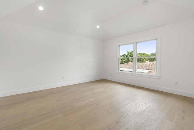 spare room featuring light hardwood / wood-style floors and lofted ceiling