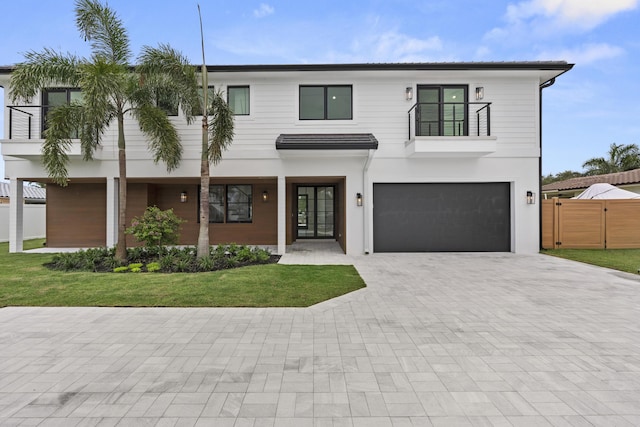 view of front facade featuring a garage, a balcony, and a front yard