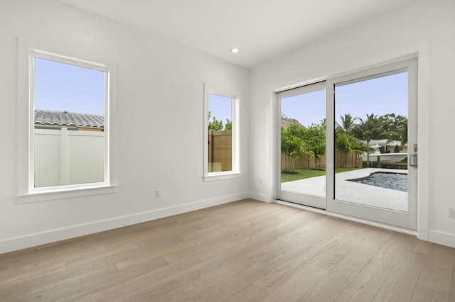 spare room featuring a wealth of natural light and light hardwood / wood-style floors