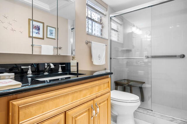 bathroom featuring crown molding, toilet, a shower with door, and vanity