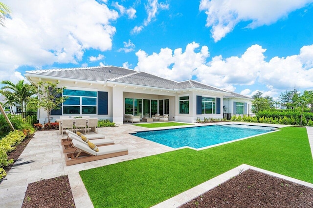 back of property featuring a fenced in pool, a patio area, and a lawn