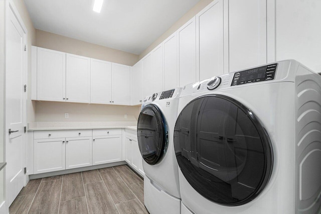 clothes washing area with cabinets and washing machine and dryer