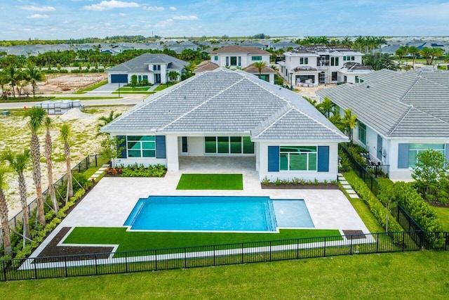 rear view of house featuring a lawn, a fenced in pool, and a patio