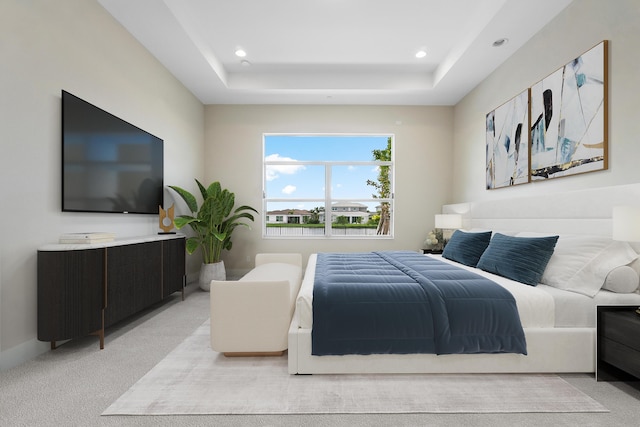 bedroom with light carpet and a tray ceiling