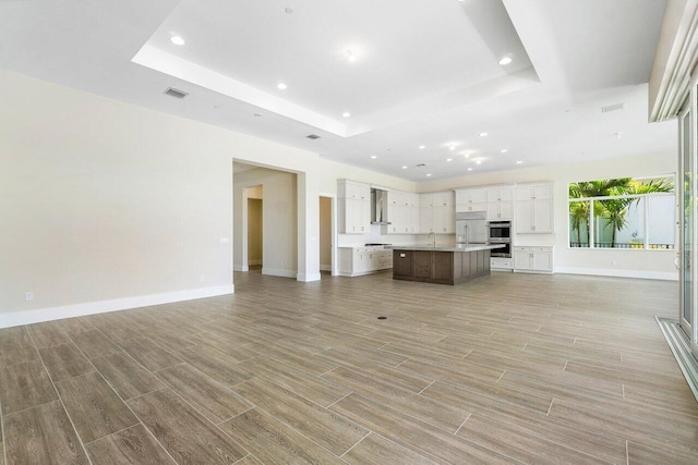 unfurnished living room featuring a raised ceiling and sink