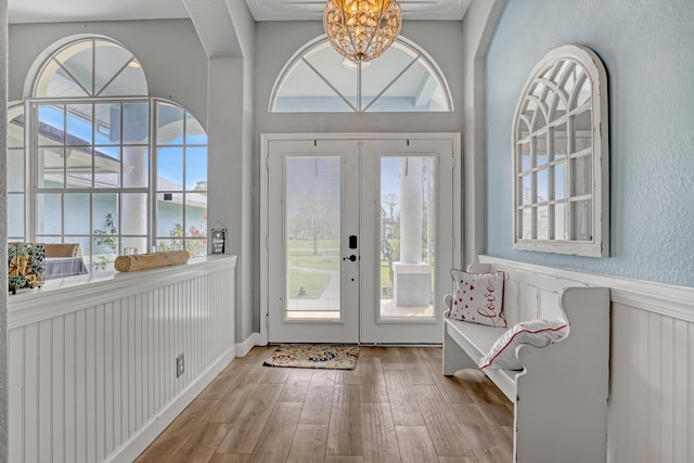 entryway with a notable chandelier, light hardwood / wood-style floors, and french doors