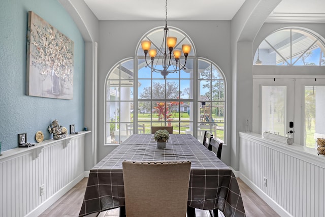 dining room with french doors, light hardwood / wood-style floors, and an inviting chandelier