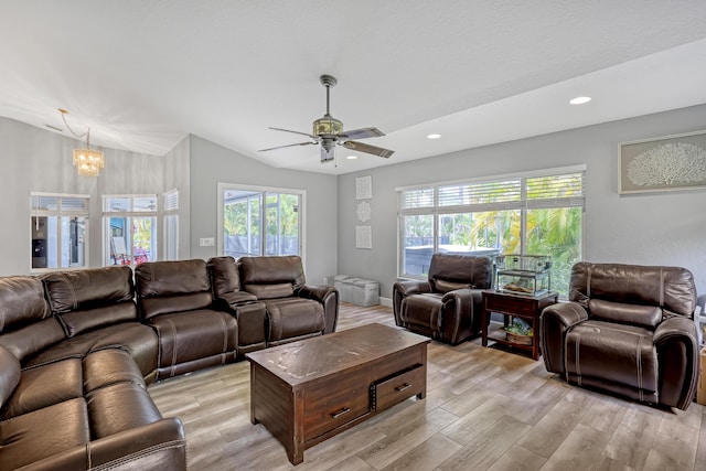 living room featuring ceiling fan with notable chandelier, light hardwood / wood-style floors, and vaulted ceiling