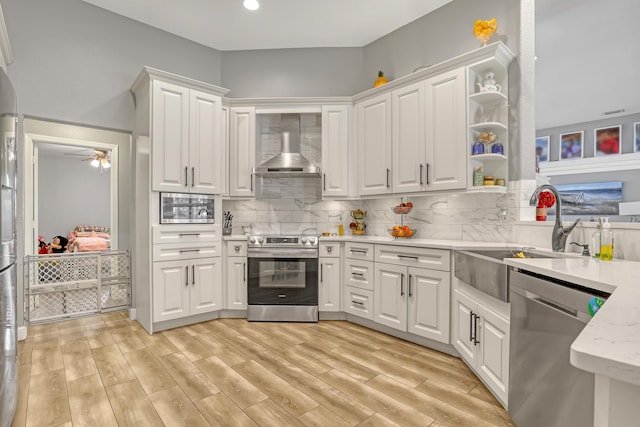 kitchen with sink, wall chimney range hood, backsplash, white cabinets, and appliances with stainless steel finishes