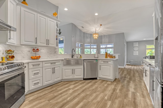 kitchen with sink, backsplash, pendant lighting, white cabinets, and appliances with stainless steel finishes