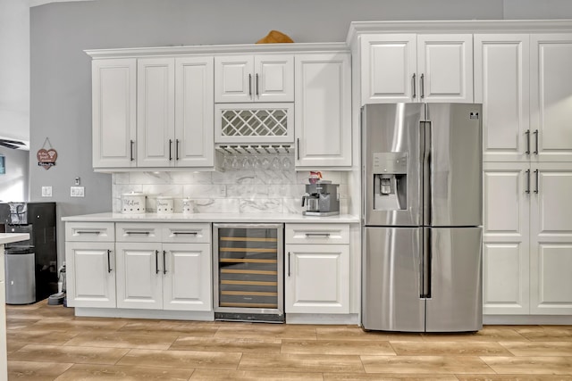 kitchen with white cabinets, stainless steel fridge with ice dispenser, tasteful backsplash, and beverage cooler