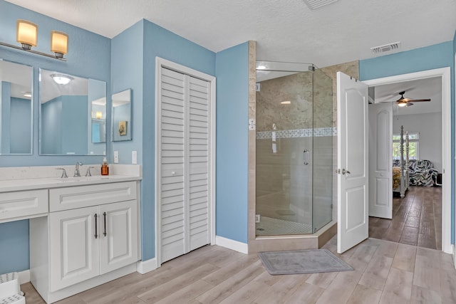 bathroom with vanity, hardwood / wood-style flooring, ceiling fan, a textured ceiling, and a shower with shower door