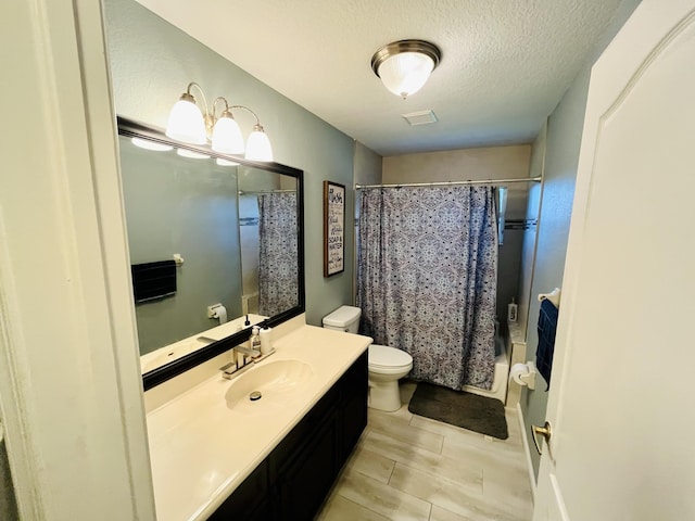 full bathroom with shower / tub combo with curtain, vanity, a textured ceiling, and toilet