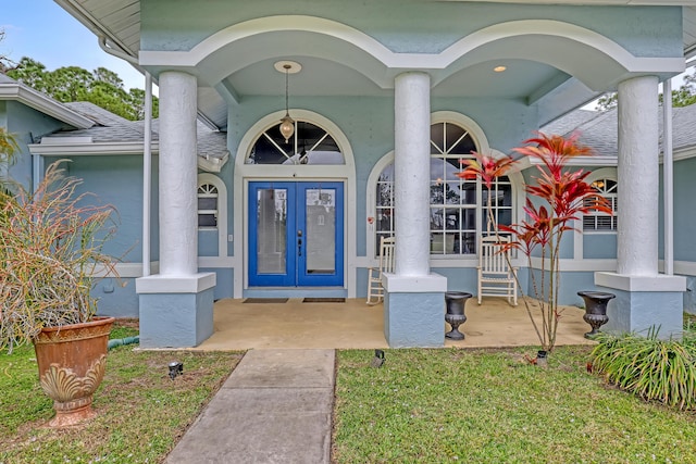 entrance to property with french doors and a lawn