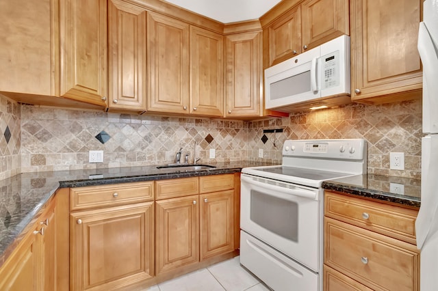 kitchen with dark stone counters, white appliances, backsplash, and light tile patterned floors