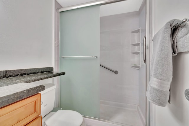 bathroom featuring vanity, an enclosed shower, and toilet