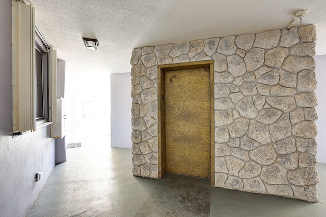 hallway with concrete flooring and a textured ceiling