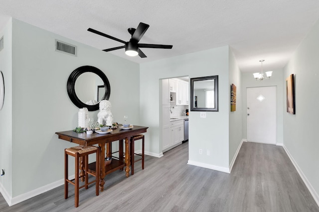 interior space with a chandelier, a textured ceiling, and light wood-type flooring