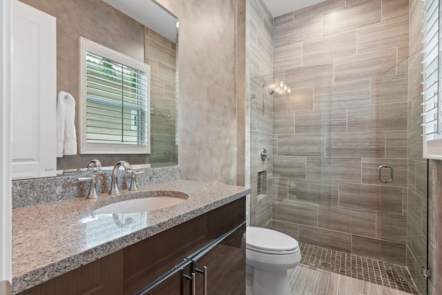 bathroom featuring a shower with door, vanity, tile patterned flooring, and toilet