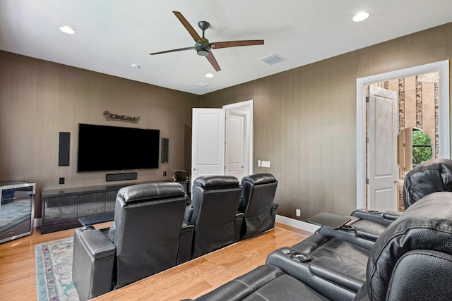 cinema with light wood-type flooring and ceiling fan