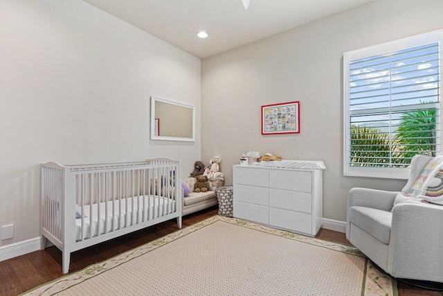 bedroom featuring hardwood / wood-style floors and a nursery area