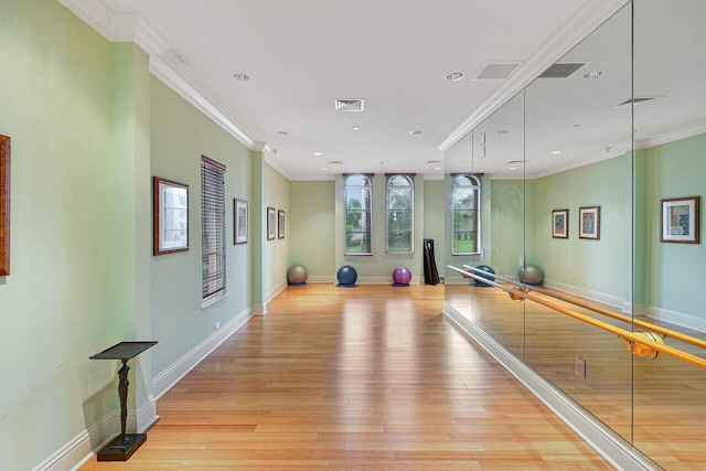 workout area featuring crown molding and light hardwood / wood-style flooring