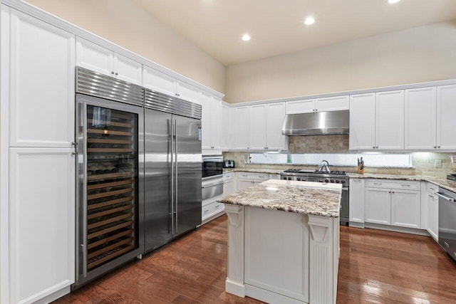 kitchen featuring tasteful backsplash, white cabinets, high end appliances, a center island, and dark hardwood / wood-style flooring