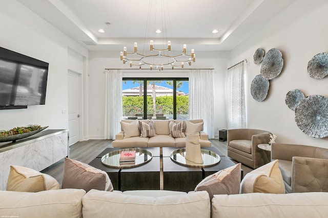 living room featuring a notable chandelier, a raised ceiling, and hardwood / wood-style floors