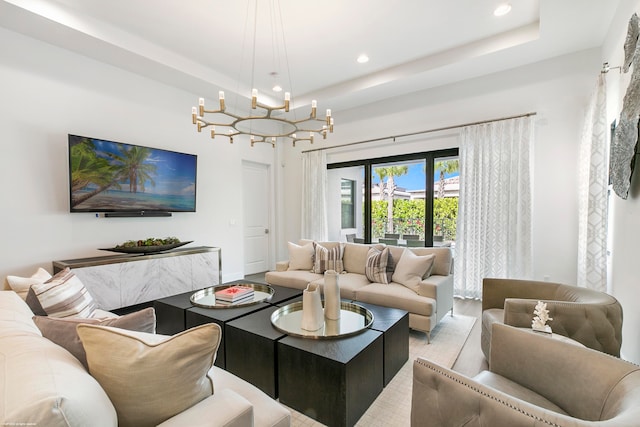 living room with a chandelier, light hardwood / wood-style flooring, and a tray ceiling