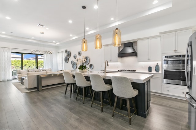 13173 Faberge Pl, Palm Beach Gardens, FL 33418 - kitchen with premium range hood, a sink, a raised ceiling, stainless steel appliances, and a kitchen bar