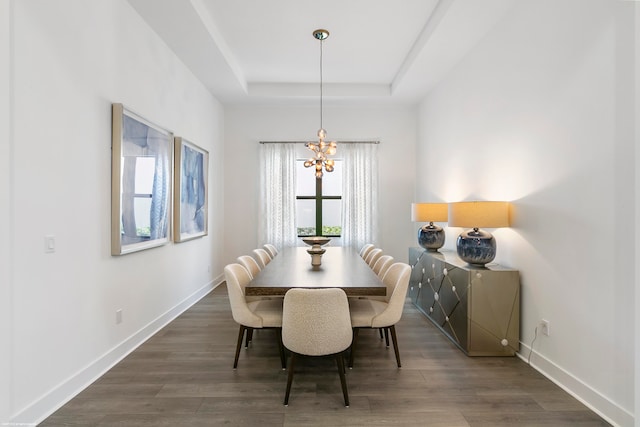 dining area featuring dark hardwood / wood-style floors, a healthy amount of sunlight, a notable chandelier, and a tray ceiling